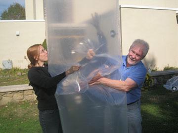 Two Biogas Workshop participants leak testing a poly-bag digester they just manufactured.